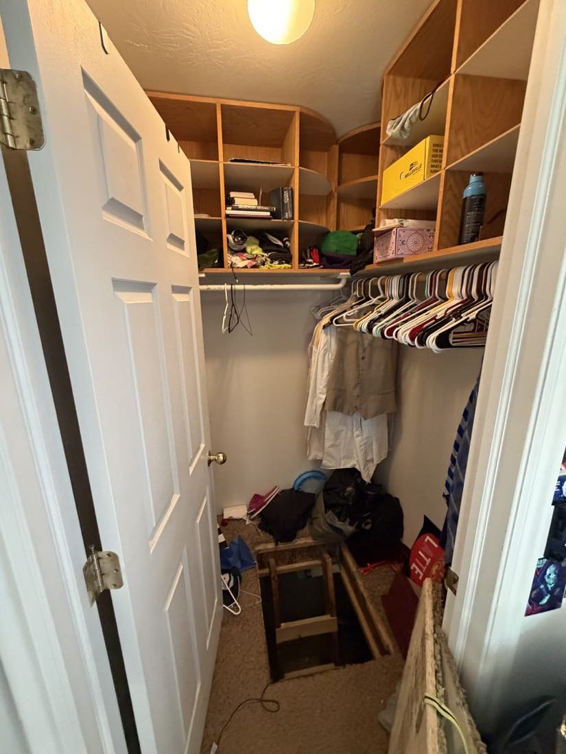 Walk-in closet packed with hanging clothes, shelving and stored boxes before an Instahaul cleanout.