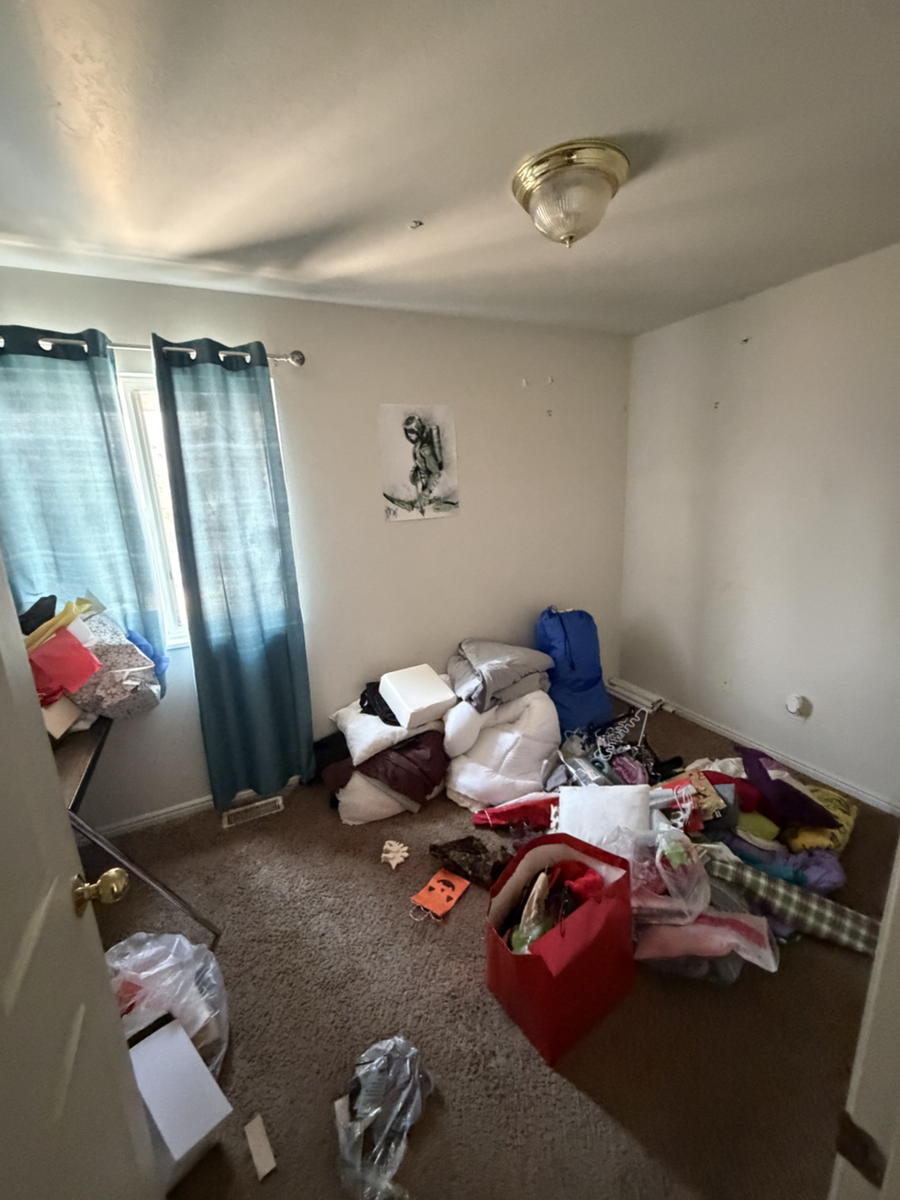 Bedroom with blue curtains and belongings before an Instahaul cleanout.
