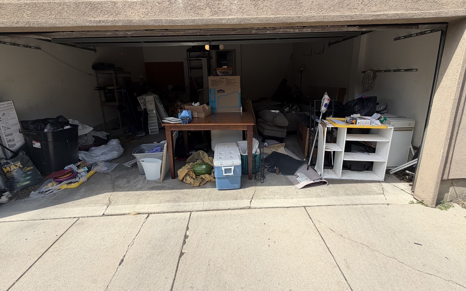 Two-car garage in Salt Lake County packed with boxes, bins, furniture and yard equipment before an Instahaul cleanout.