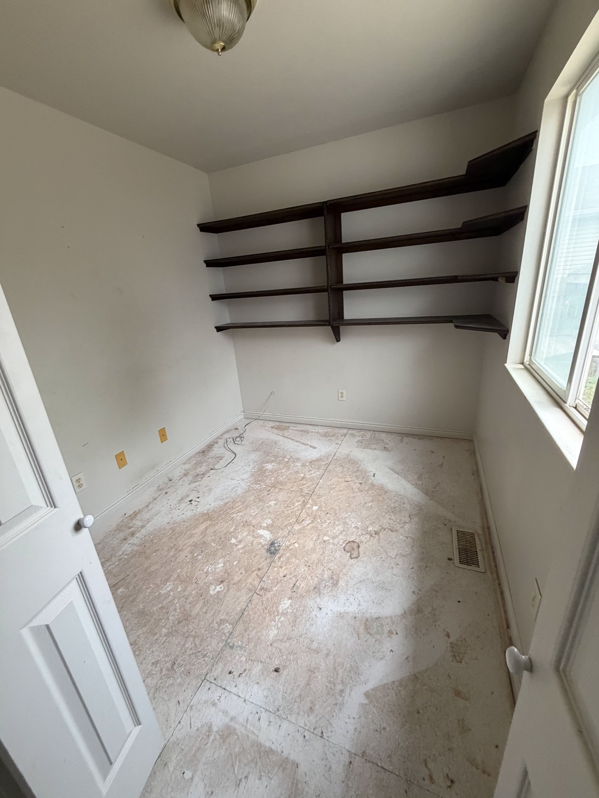 The bedroom cleared, with wall shelves remaining.